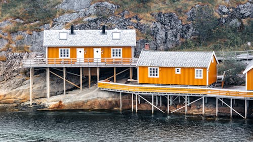 Orange Wooden Houses on Stilts on the Steep Rocky Coast