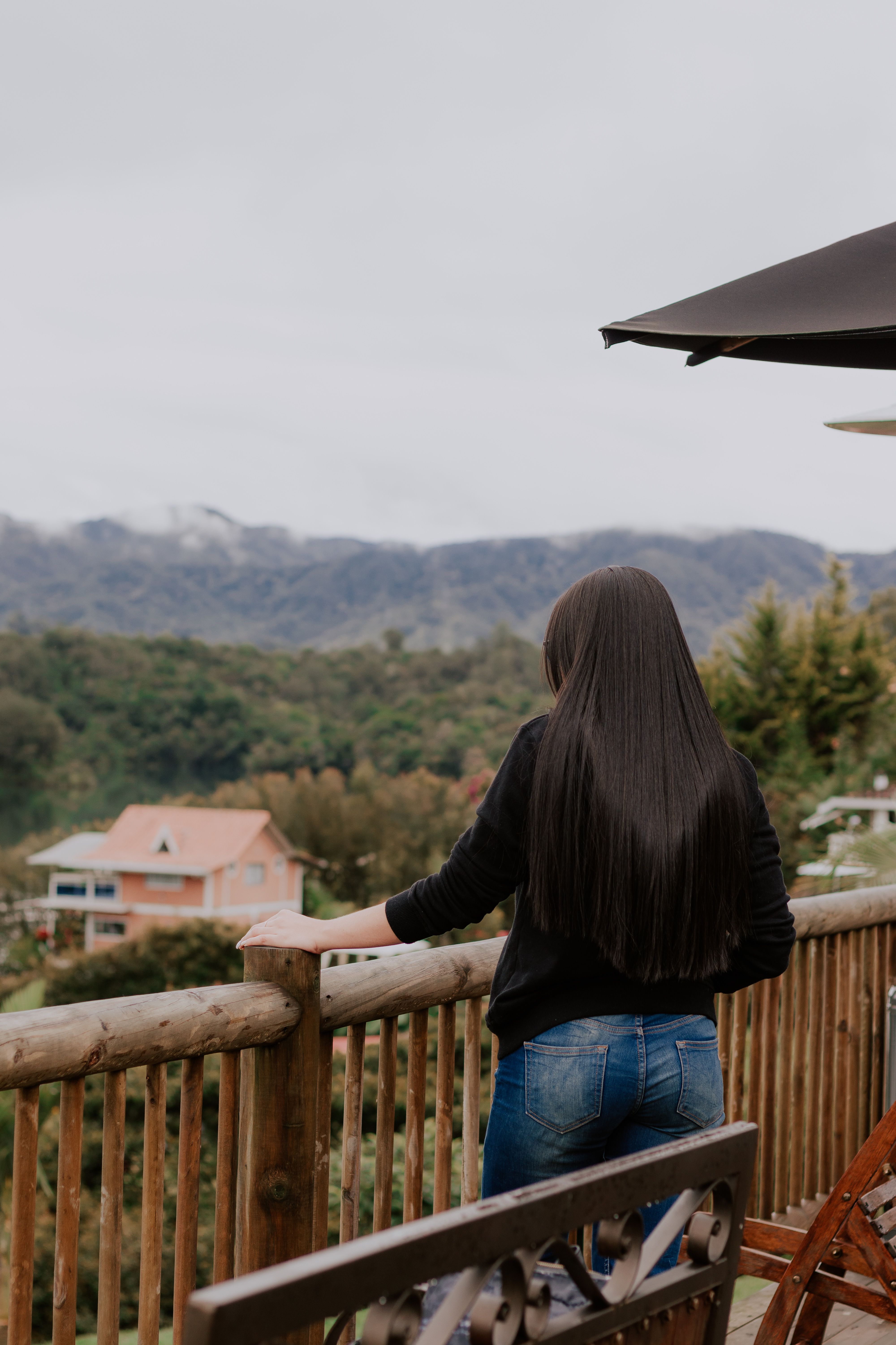 Back View of a Woman Standing on a Balcony with a Wooden Balustrade ...