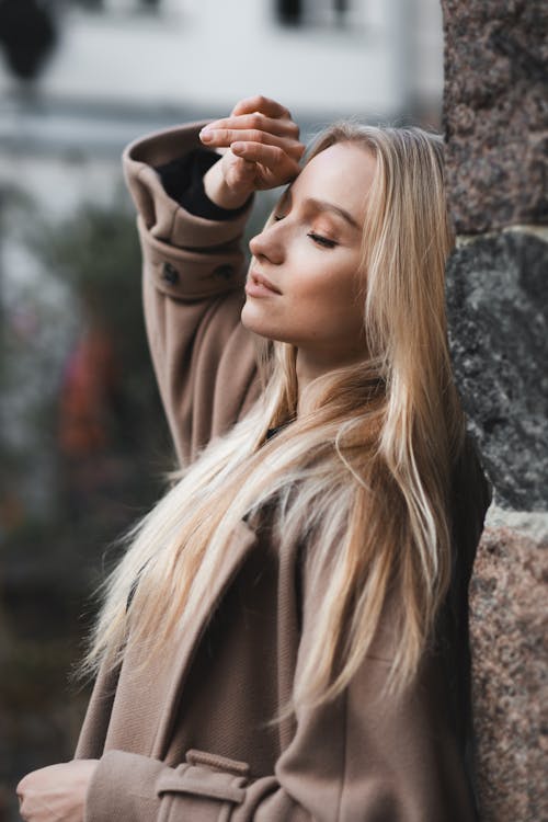 Blonde Woman in Coat Standing with Arm Raised