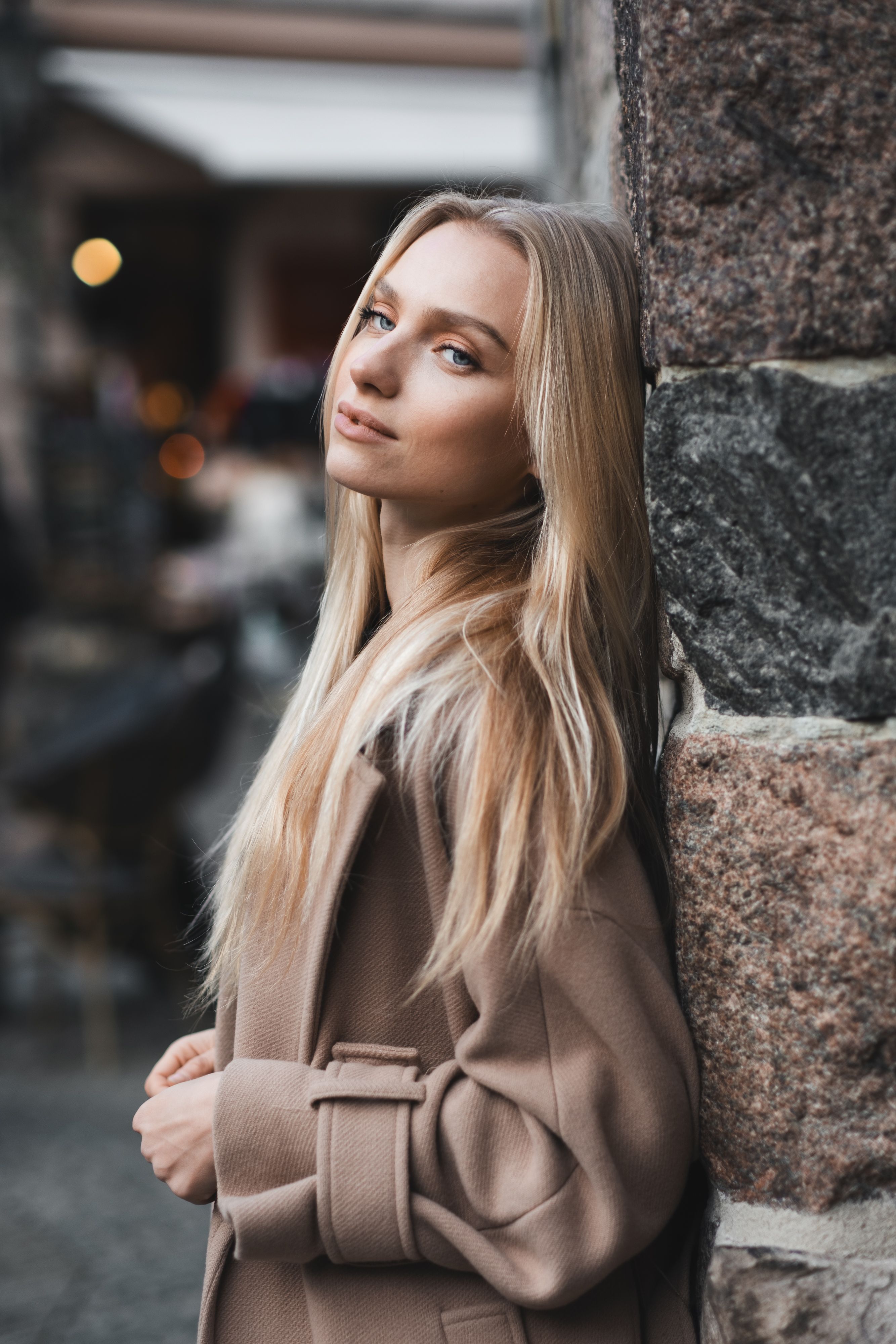 Free A blonde woman leaning against a stone wall Stock Photo