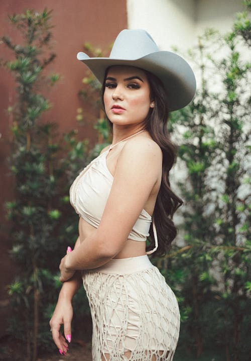 Young Woman Wearing a Dress and Hat Posing Outside 