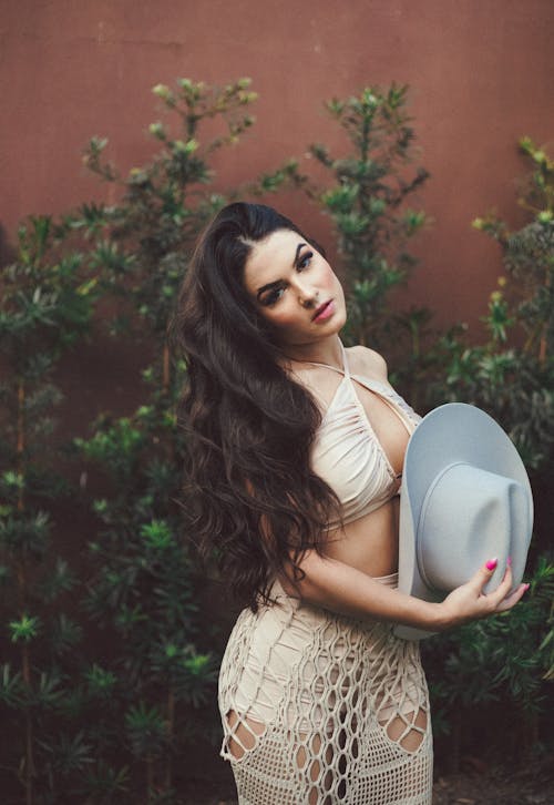 Young Woman Wearing a Dress and Hat Posing Outside 