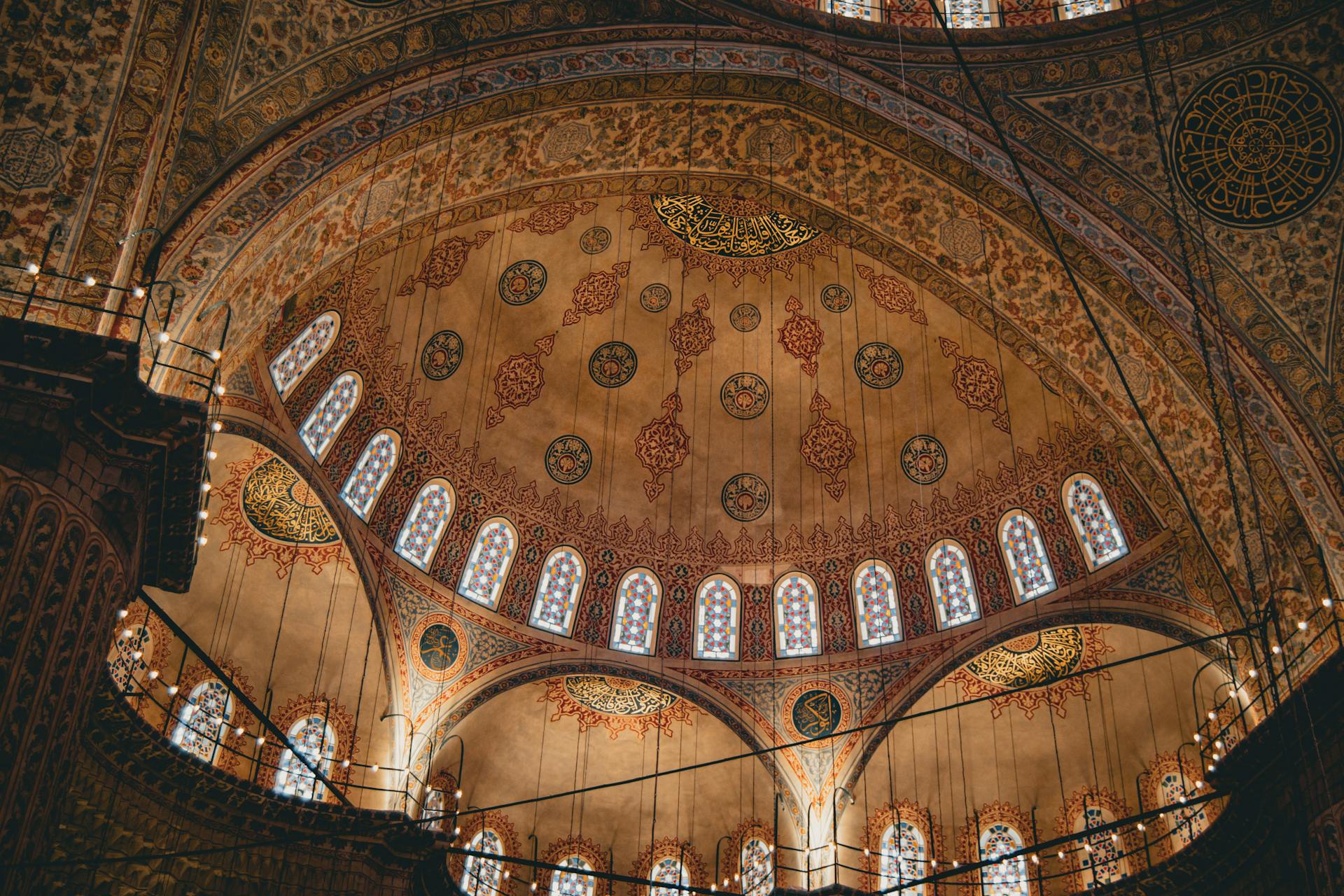 Intricate mosque interior featuring detailed artwork on a vaulted ceiling, emphasizing Islamic architectural elegance.