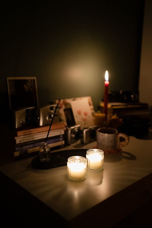 Free A warm, inviting reading nook featuring candles, books, and a mug in soft lighting. Stock Photo