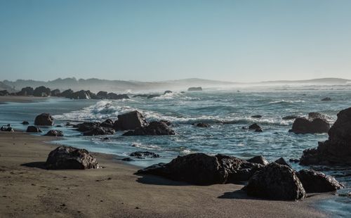 Free A serene ocean view showcasing rugged rocks, waves, and a clear sky, perfect for nature themes. Stock Photo
