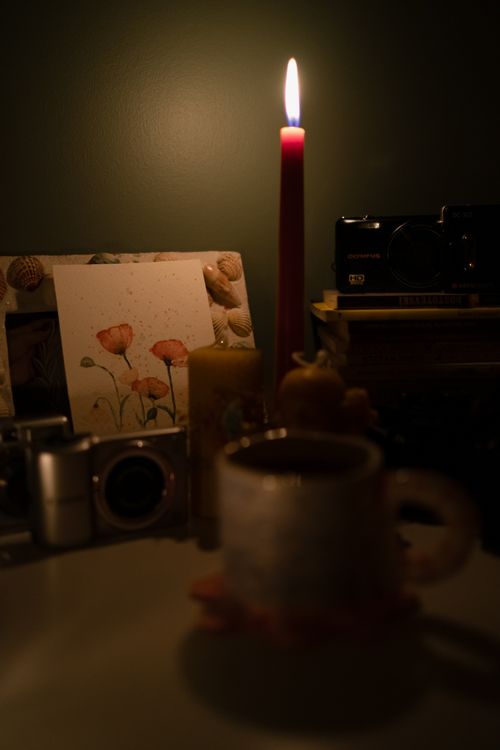 Free A warm, candlelit desk scene with vintage cameras, art, and a mug in Ankara. Stock Photo