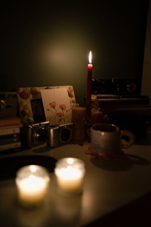 Free Warm, dim-lit scene of a table with candles, books, and vintage cameras in Ankara, Türkiye. Stock Photo