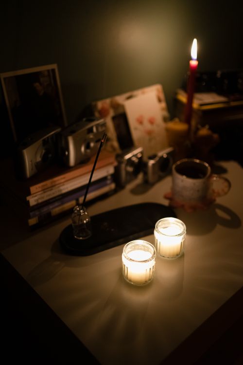 Free Warm candlelight illuminating a desk with books, cameras, and a mug in Ankara, Türkiye. Stock Photo