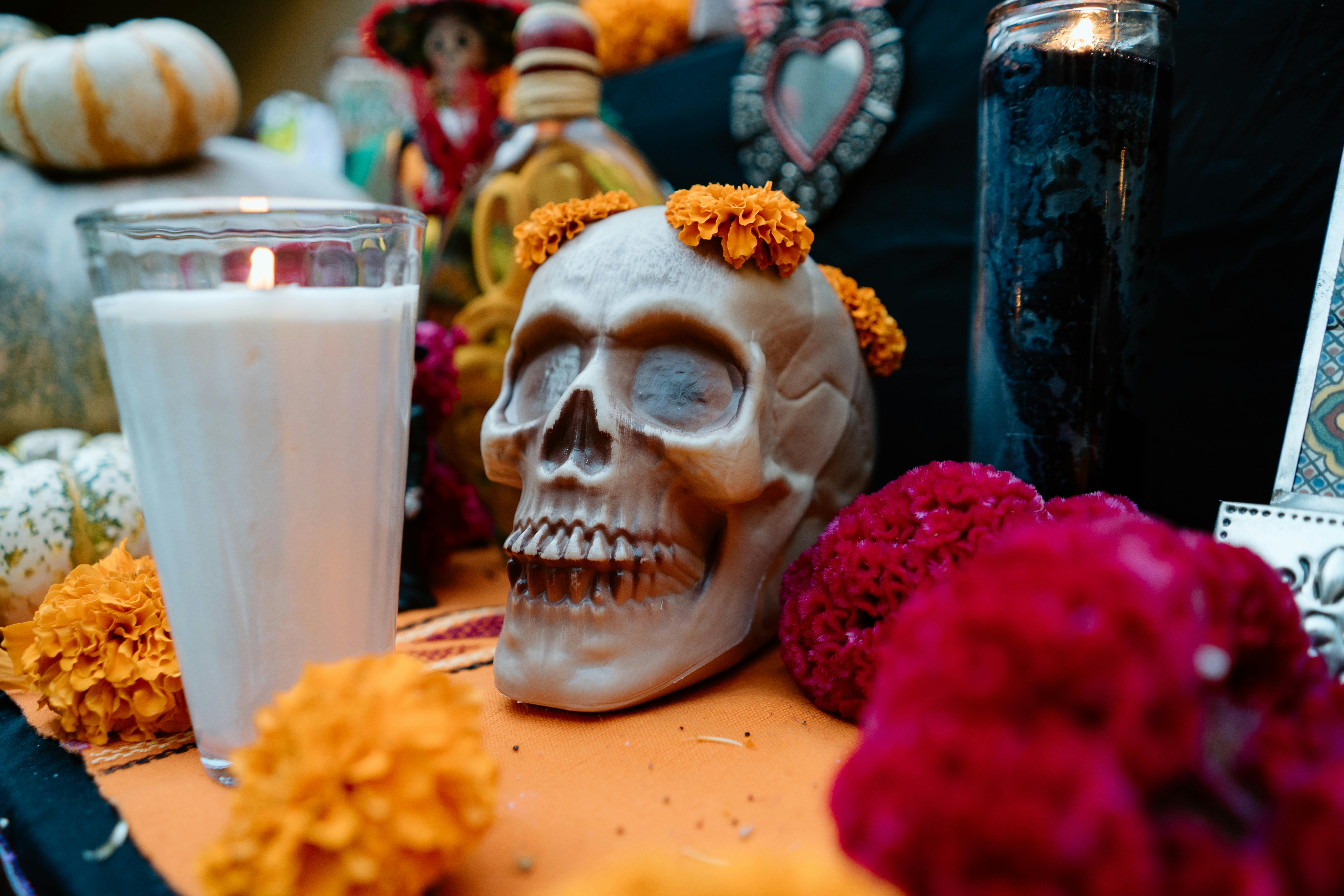 Colorful Dia de Muertos altar with painted skull adorned with orange marigold flowers and lit candles celebrating Mexican Day of the Dead tradition