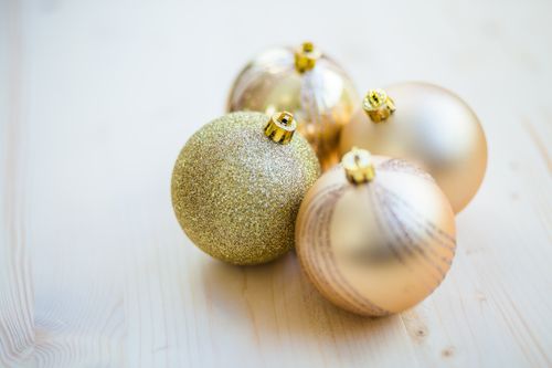 Free A close-up of gold Christmas ornaments with different finishes on a light wooden surface. Stock Photo