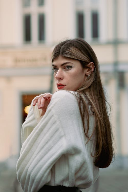 Model in a White Sweater with Wide Sleeves Posing on the Sidewalk