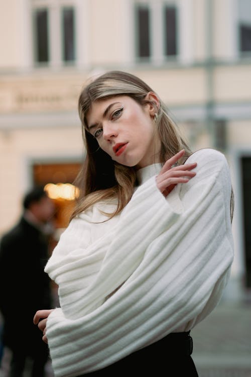 Young Woman in a White Sweater Posing on a Street in City 