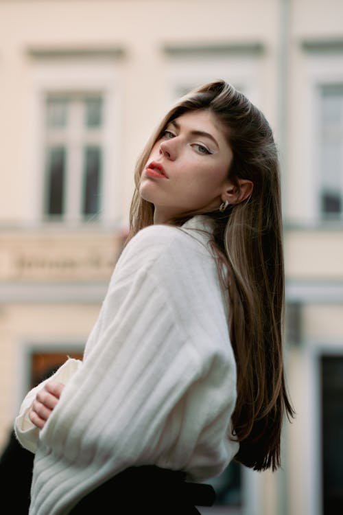 Young Woman in a White Sweater Posing on a Street in City 