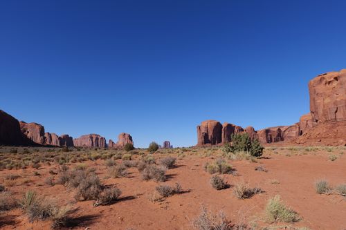 Free Scenic view of Monument Valley's red rock formations under clear blue sky. Stock Photo