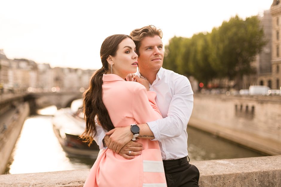 A romantic couple embraces by the river in Paris, capturing a timeless moment of togetherness.