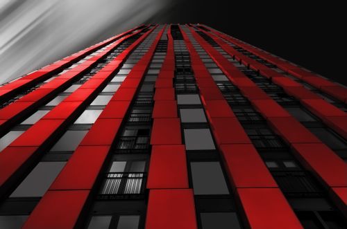 Free Low angle view of a striking red high-rise building against a dramatic sky. Stock Photo