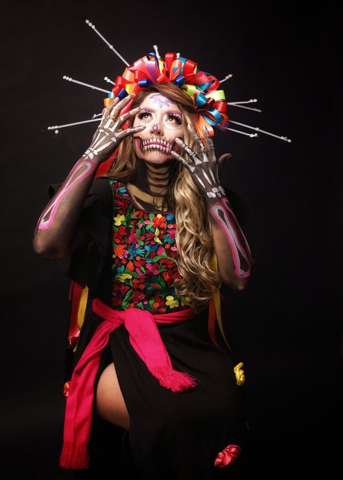 Free Vibrant Day of the Dead costume and makeup; woman posing with traditional dress in a studio setting. Stock Photo