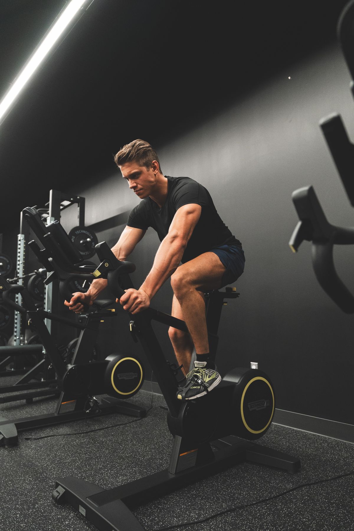 Man riding a studio exercise bike in a dark gym