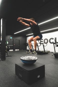 Athlete practicing jump training on balance pod in modern gym setting.