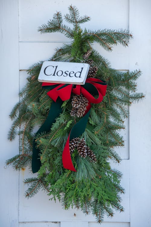 Christmas Decoration Made of Pine Branches Hanging on the Door with a Closed Sign