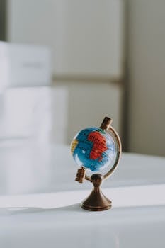 Close-up of a miniature globe on a wooden desk in an interior setting.