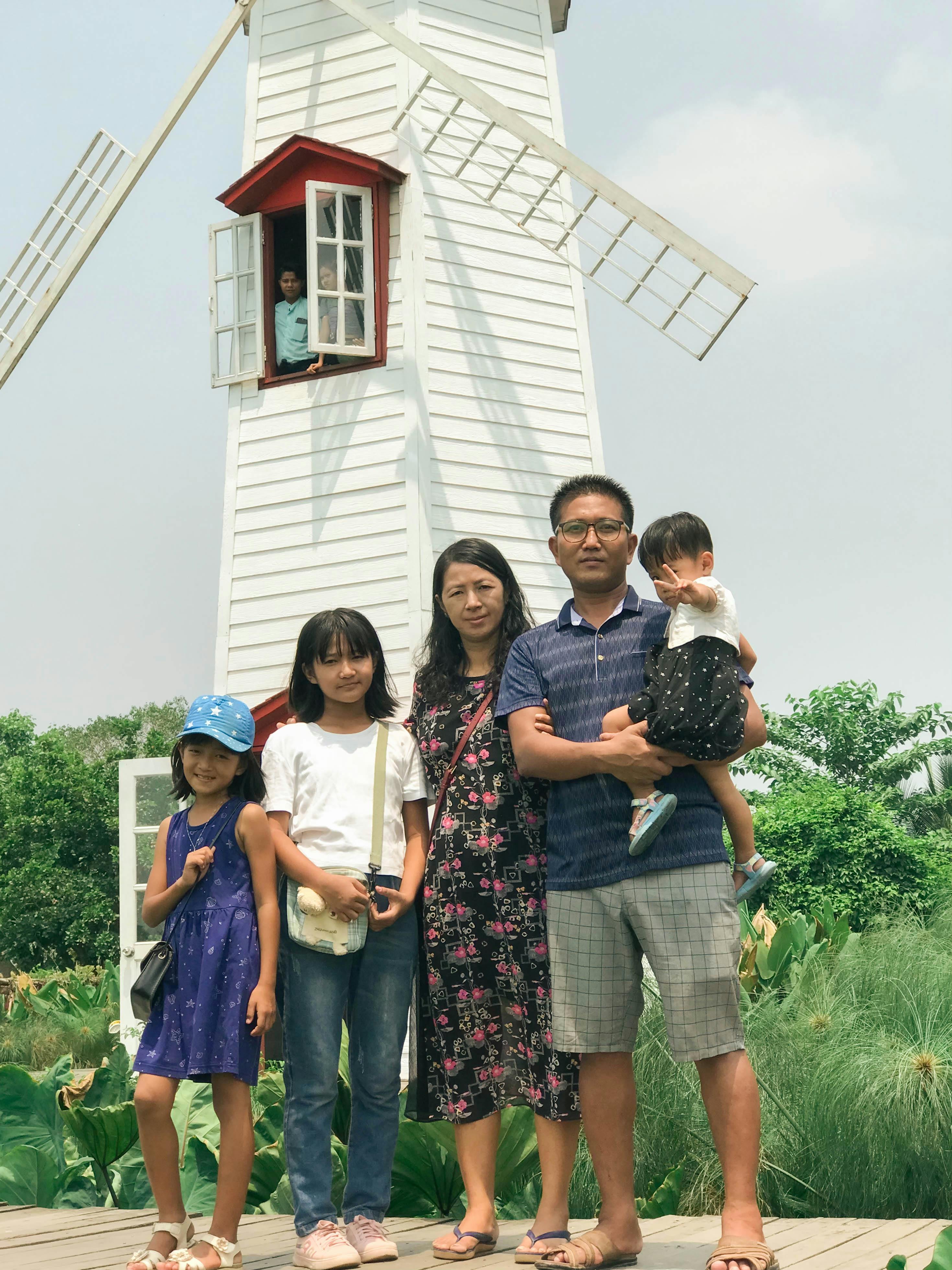 a family poses for a photo in front of a windmill