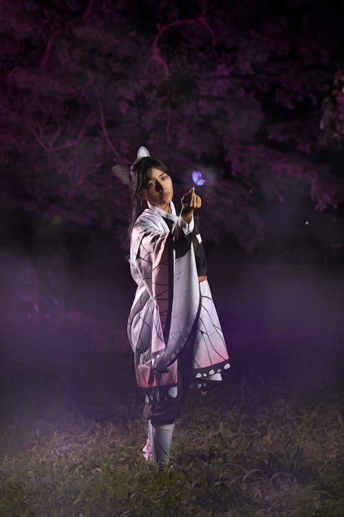 Young Woman in a Kochou Shinobu Cosplay Standing in a Park at Night 