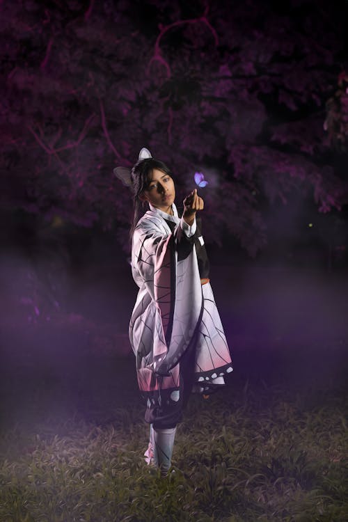 Young Woman in a Kochou Shinobu Cosplay Standing in a Park at Night 