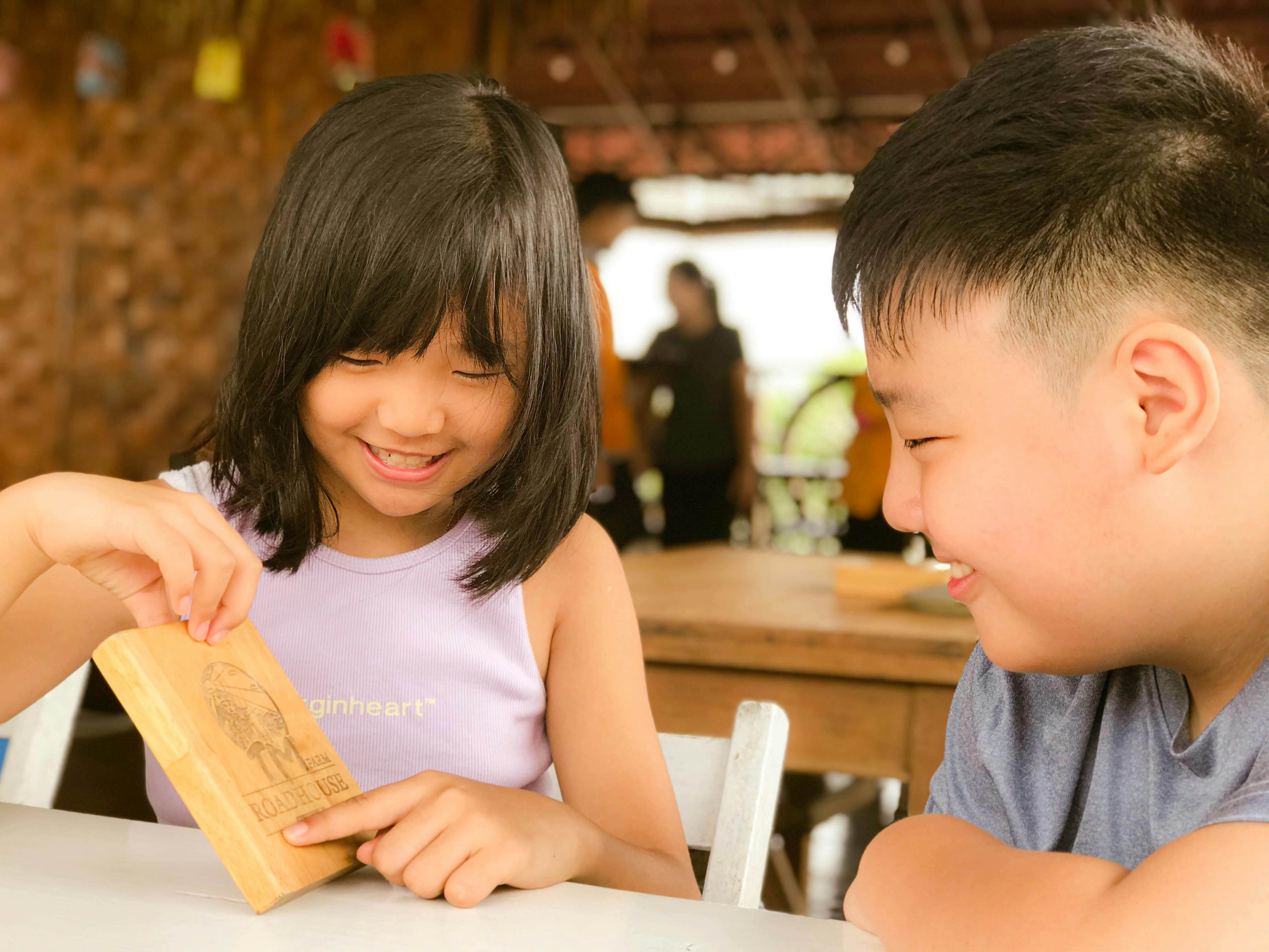 two children sitting at a table with a wooden box