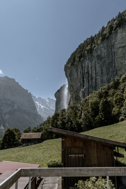 Scenic view of a Swiss village with a majestic waterfall and lush greenery in the valley.