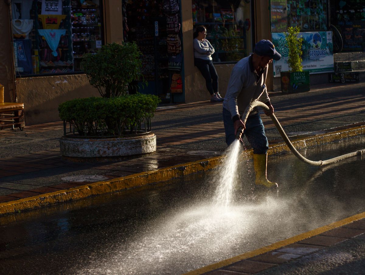Worker cleaning outdoor surface with hose