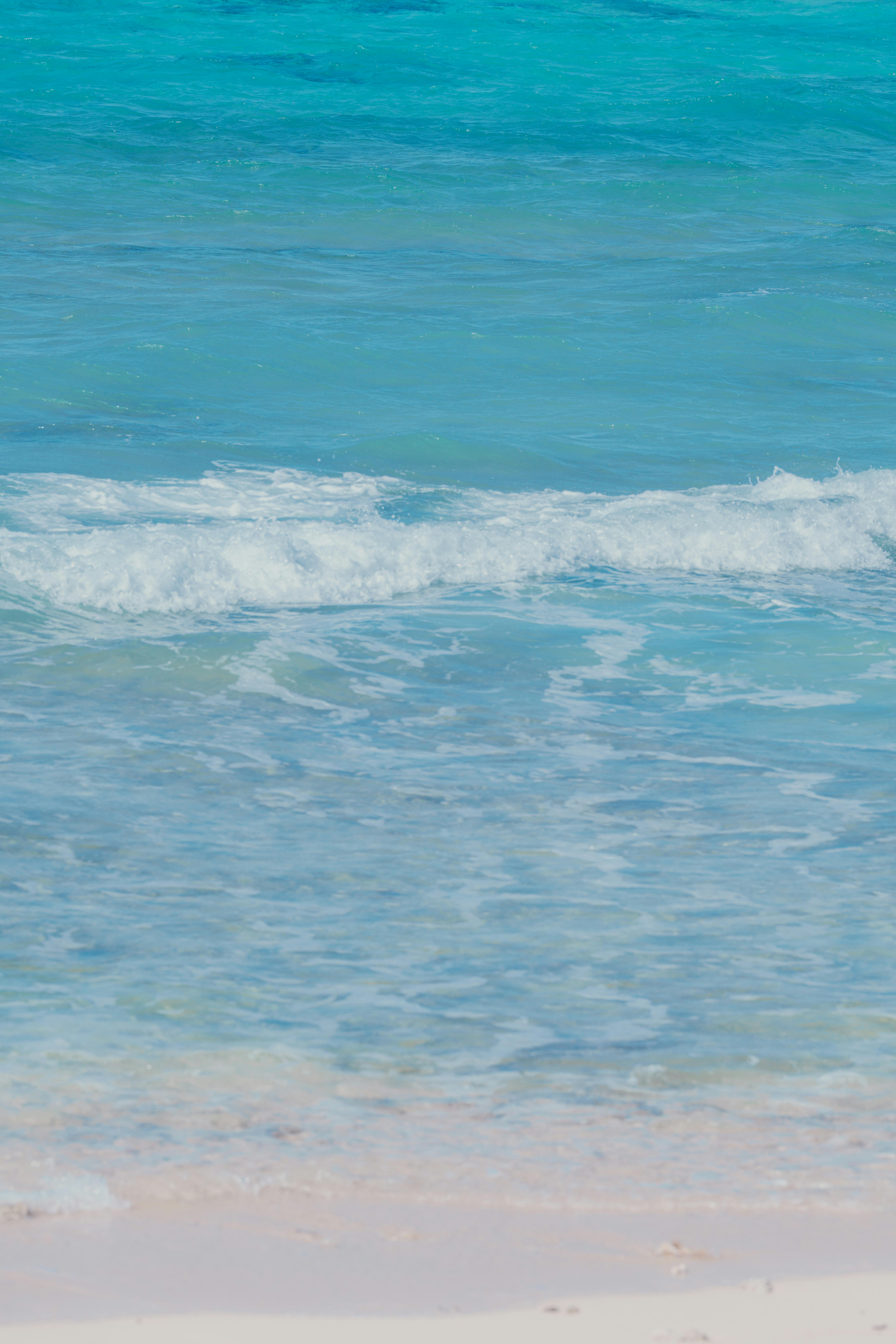 Peaceful beach scene with gentle waves and clear blue water creating a serene atmosphere.