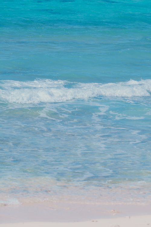 Free Peaceful beach scene with gentle waves and clear blue water creating a serene atmosphere. Stock Photo