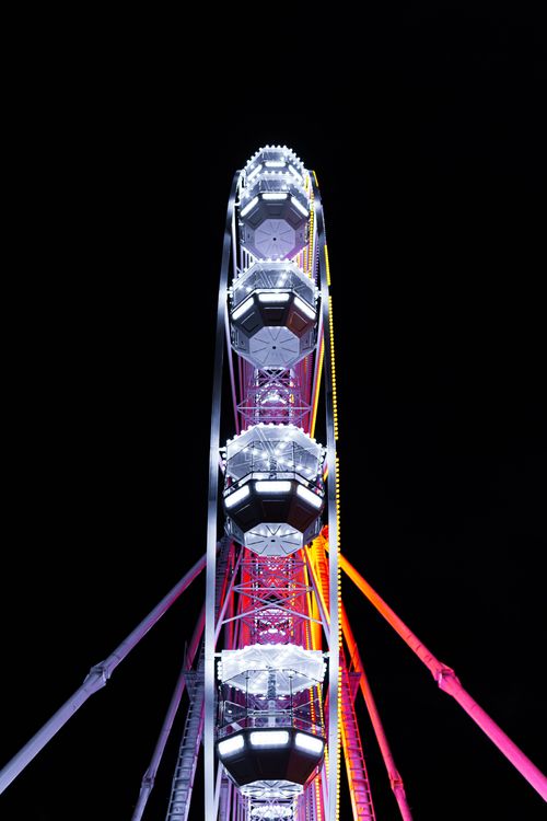Free A vibrant ferris wheel illuminated beautifully against a dark night sky, showcasing glowing lights. Stock Photo