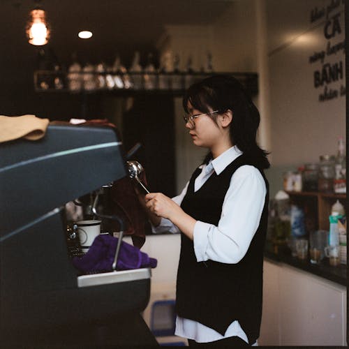 Woman in Shirt and Vest Working in Cafe