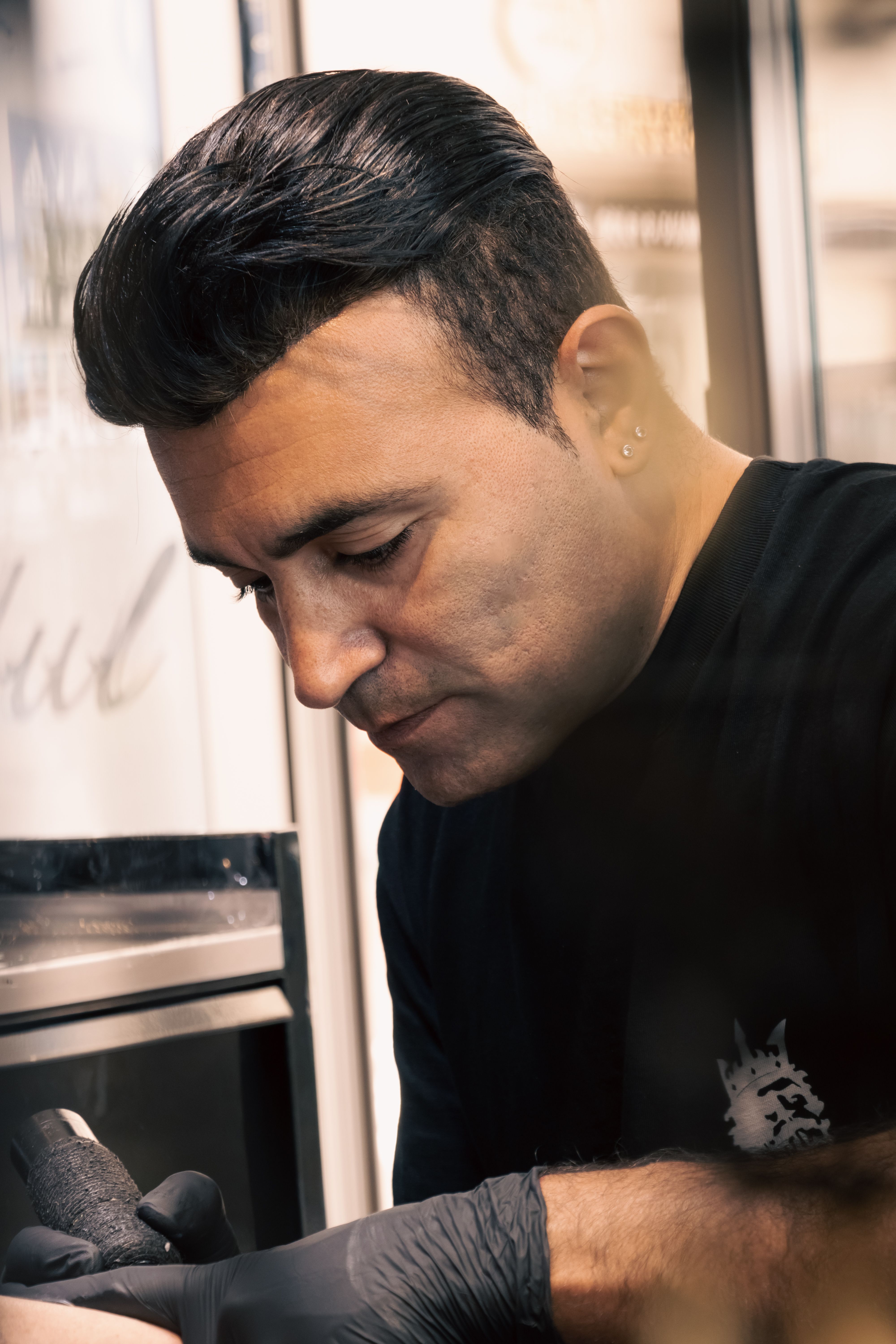 Tattoo artist concentrating on work in Aydın studio, showcasing his craft with precision.