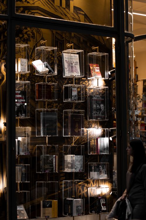 Free A woman walks past a bookstore window with illuminated book displays in Belgrade, Serbia. Stock Photo
