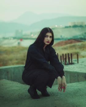 Young woman in black jumpsuit posing outdoors with a cinematic feel.