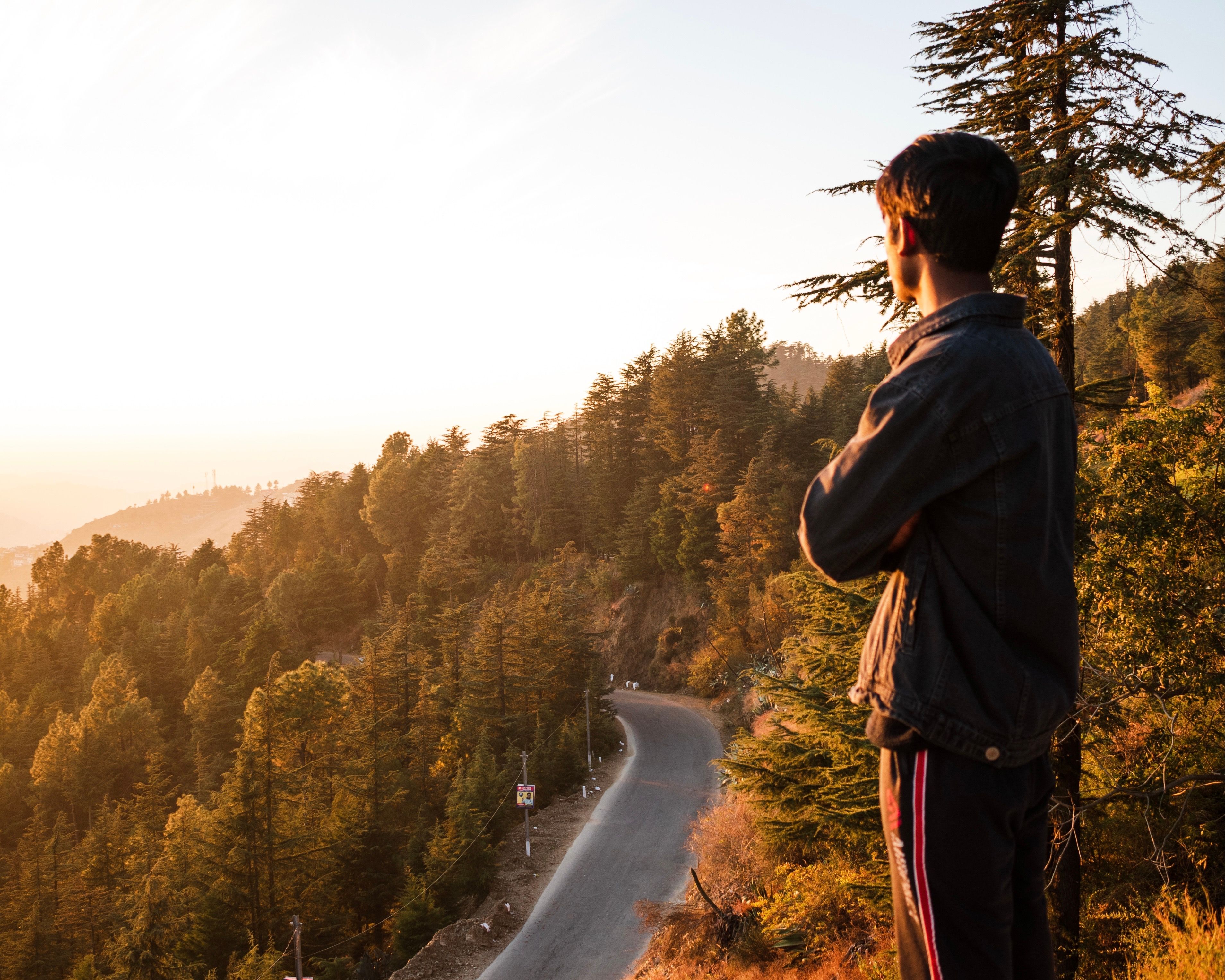 Man Standing on a Mountainside Above the Road Enjoying the Sunset ...