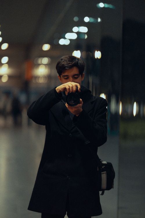 Free A young man captures a moment in a dimly lit hallway with reflections. Stock Photo