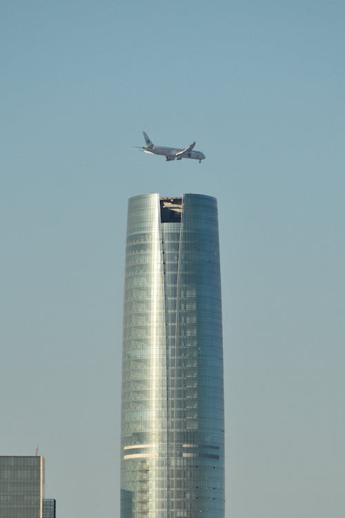Free Airplane Flying over Skyscraper Stock Photo