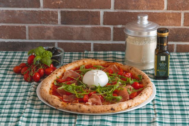Pizza à la burrata, à la roquette et au jambon cru servie sur une table rustique