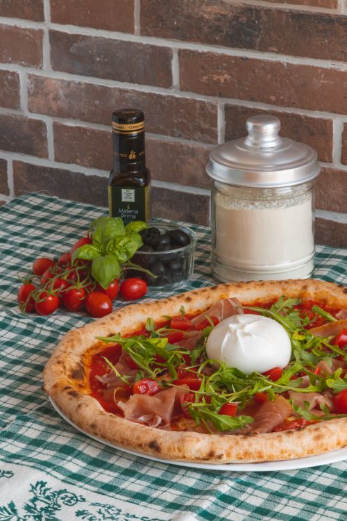 Free Mouthwatering Italian pizza with fresh mozzarella, cherry tomatoes, and arugula on a checkered tablecloth. Stock Photo