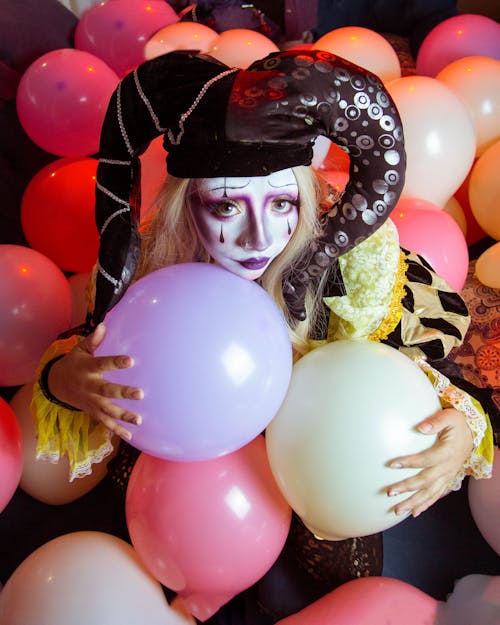 Woman in Jester Hat and Makeup among Balloons