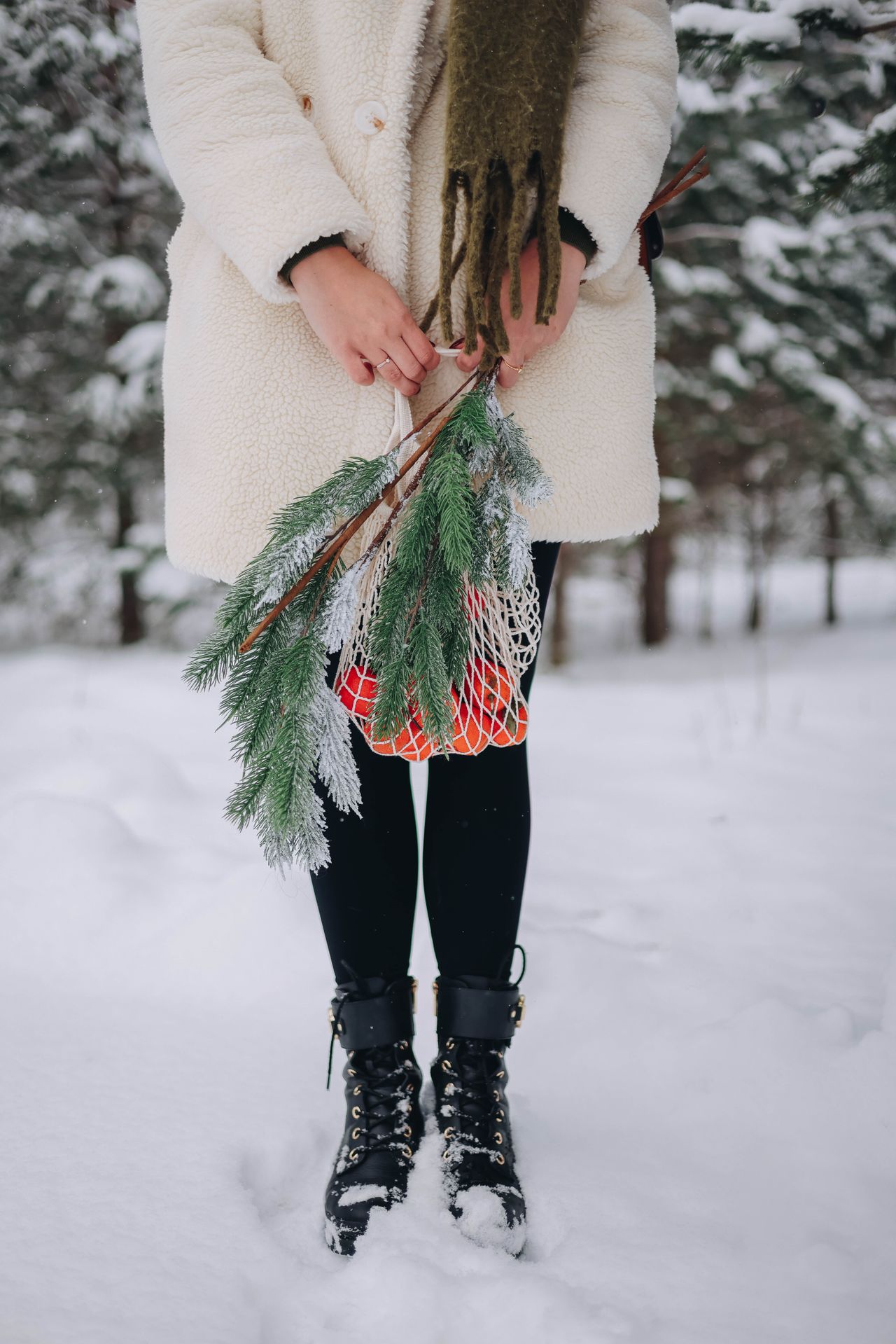 Woman in a cream winter coat with black tights and ankle boots in the snow