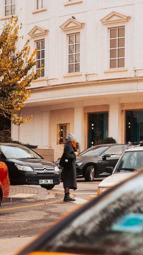 Woman Standing on the Side of the Street among the Cars 