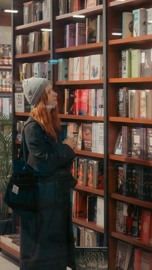 Woman Looking at Books on the Shelves in a Library 