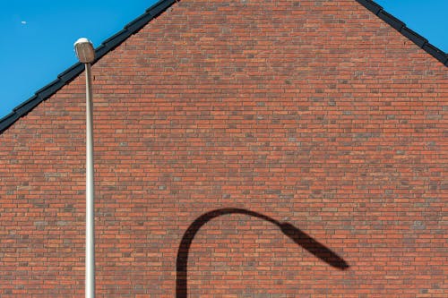 Streetlight Casting Shadow on Red Brick Wall