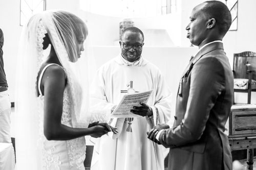 Free Black and white photo of a couple getting married by a priest indoors. Stock Photo