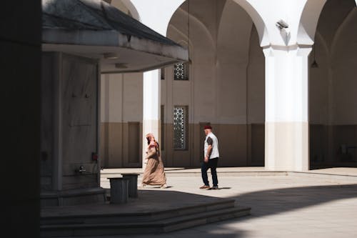 Man and Woman Walking on Mosque Courtyard